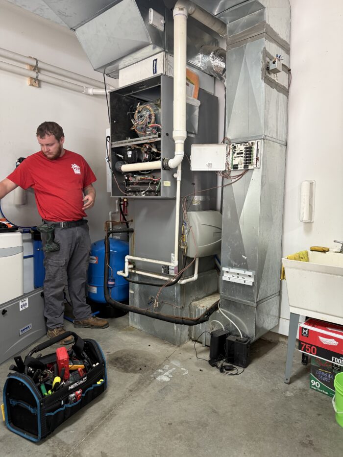 Roehm Team member in front of furnace with the front panel removed.